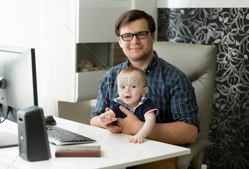 坐在家中的年轻男自由职业者坐在家中抱着他1岁的儿子高清图片下载 正版图片 摄图网