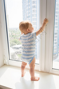 男孩站在窗台上试图打开窗户图片
