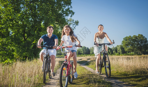 10岁女孩与父母一起在野外骑自行车图片