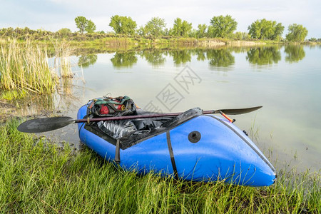 一辆蓝色木车用于探险或冒赛的单人轻型木筏在春季风景的湖岸上有一个单艇桨图片