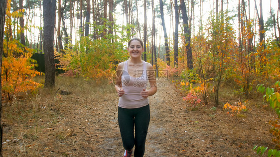 流着笑的体育女跑在秋天的森林里图片