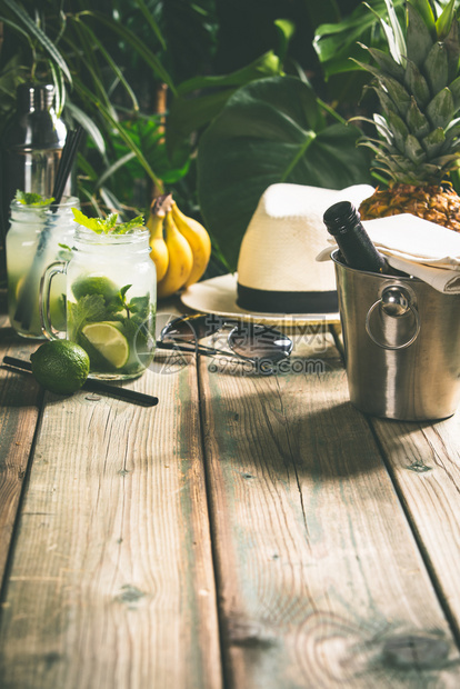 暑假概念热带树叶背景上的白帽饮料和热带水果图片