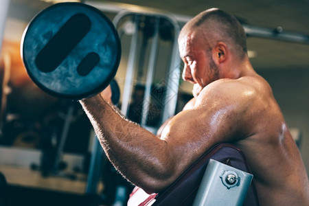 无肌肉的男子在健身房里举重汗流满身体力和举重图片