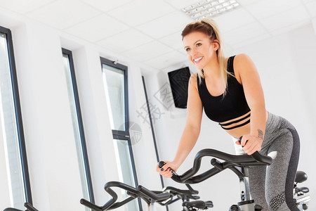 年轻美女在健身房骑动感单车锻炼身体图片