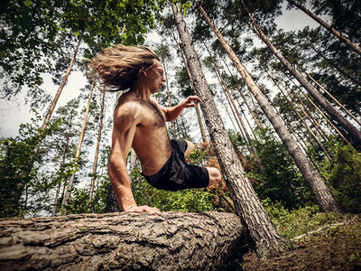 年轻人跳过森林的树干夏季露天自然与由概念低角度视图片