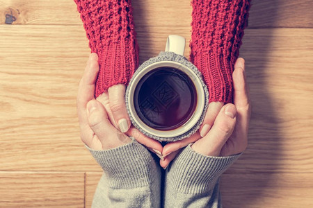 一对情爱的侣用热茶杯来亲的手穿着可爱羊毛跳跃者爱的情侣用热茶杯来亲的手图片