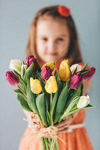 年轻女孩拿着一帮多彩的郁金香母亲和一天的礼物父母感谢年轻女孩拿着母亲和一天的礼物图片
