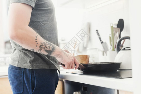 男人站在炉子前用煎锅做饭图片