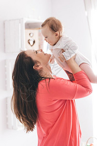 年轻女把她的婴抱起养育子女的概念抚养孩子图片