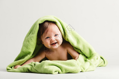 孩子画画被绿色温暖的毯子覆盖着婴儿女孩躺在她的肚子上舒适和照顾背景