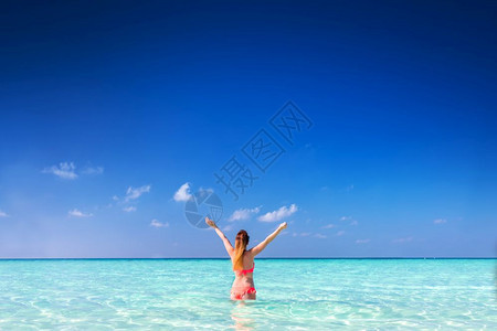 站在海洋中的美丽年轻女举起双手图片