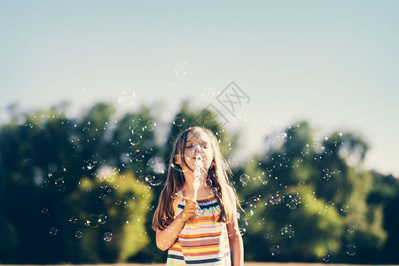在公园吹肥皂泡的小女孩夏季户外活动童年小女孩在公园吹肥皂泡的小女孩图片