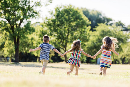 三个小孩跑在绿地上手牵手奔跑图片