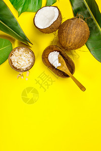 椰子油热带叶和黄底平地的新鲜椰子背景图片