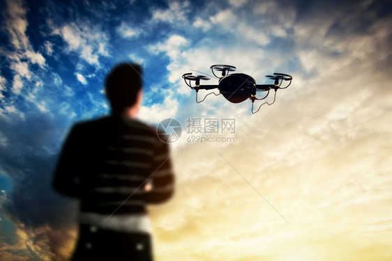 日落时一名男子操作无人机空中摄像工作图片