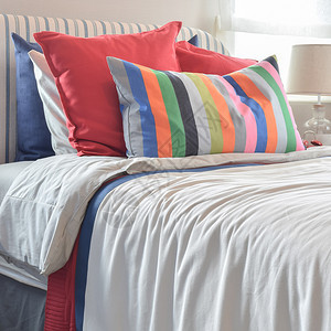 头巾上挂着彩色枕头和白床单上带色枕头和条的白床单图片