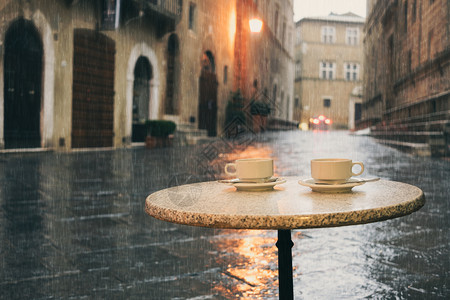 旧欧洲城市的雨天湿咖啡桌两杯图片