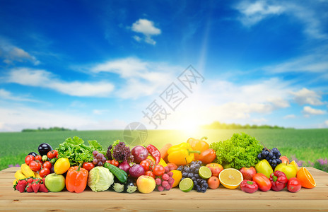 在春田和明蓝天空的背景下木板上的蔬菜和水果图片