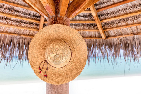 太阳帽挂在热带海滩的遮阳伞上印度洋马尔代夫背景图片