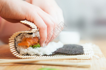 准备滚动寿司鲑鱼鳄梨海草米和木制桌上的筷子准备鳄鱼大米和木制桌上的筷子图片