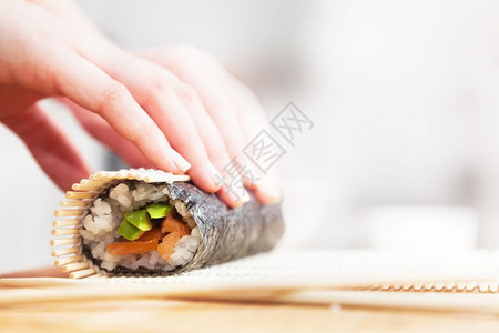 准备滚动寿司鲑鱼鳄梨海草米和木制桌上的筷子准备鳄鱼大米和木制桌上的筷子图片