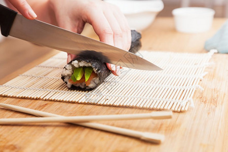 准备寿司切片鲑鱼鳄梨海藻米和木制桌上的筷子准备寿司鳄鱼大米和木制桌上的筷子图片