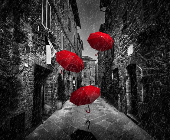 在意大利托斯卡尼的一个老意大利小镇上黑白与红在意大利托斯卡尼的一个老意大利城镇上乌姆贝拉在黑暗街道上随风和雨飘扬图片