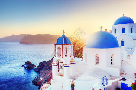 希腊圣托里尼岛奥亚镇日落时传统和著名的白色房子和教堂在爱琴海的卡尔德拉岛上空有蓝色圆丘陵图片
