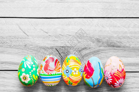 复活节手工制作的鸡蛋在木制桌子上涂多彩的花岗图案图片