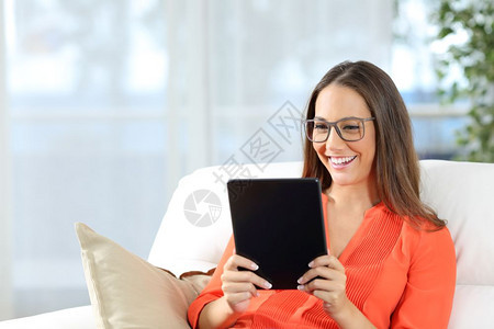 身戴眼镜的随妇女在家中沙发上看平板坐在沙发上背景有窗户图片