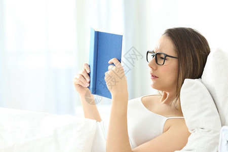在家床上看书时戴着眼镜的累女人图片