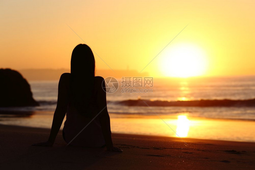 坐在海滩沙上的一个女人背影坐在海滩的沙上日出时看太阳与地平线和海洋在背景中高清图片下载 正版图片 摄图网