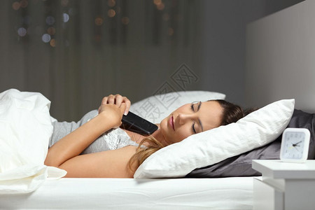晚上在家用手机床上睡觉的女人图片
