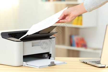 在桌子上的打印机拿出文件图片