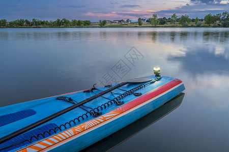 黄昏过后在平静的湖上起立用桨安全带和导航灯图片