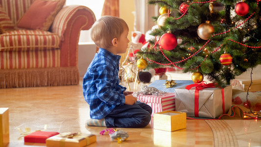 早上坐在圣诞树下的小男孩图片