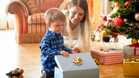 微笑的母亲看着她儿子打开圣诞礼物和美丽的微笑母亲看着她儿子图片