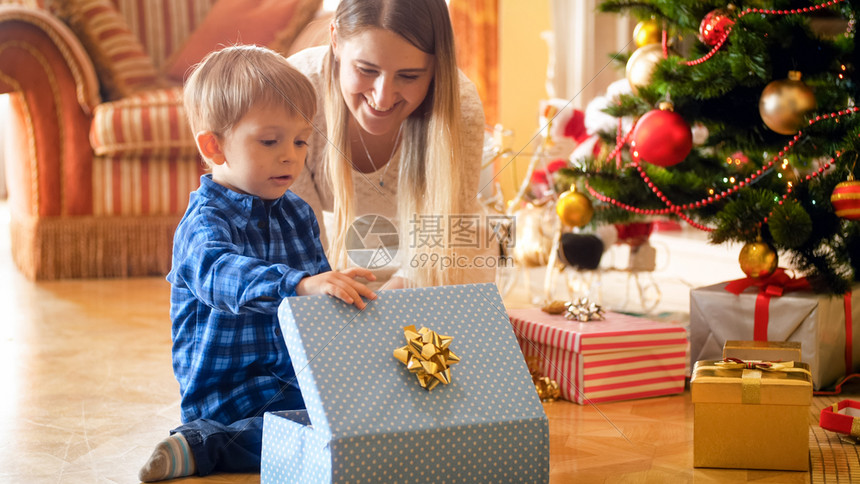 与年轻母亲一起看圣诞礼物盒的托德勒男孩与年轻母亲一起看圣诞礼物盒的可爱幼儿男孩图片