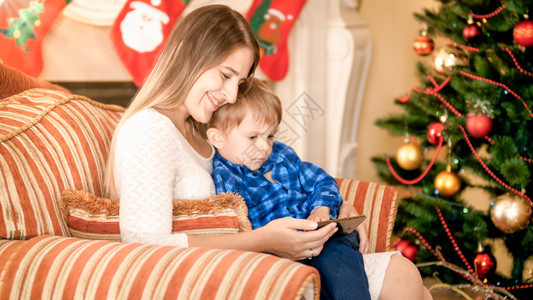母亲和孩子坐在沙发上观看手机图片