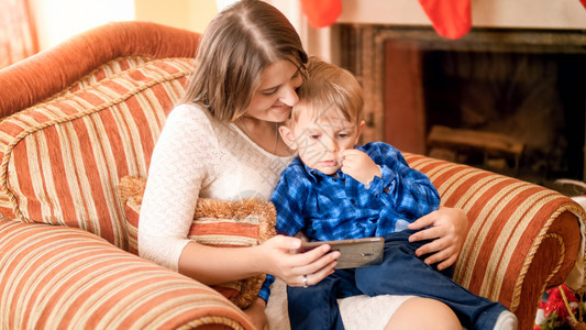 母亲和孩子坐在沙发上观看手机图片