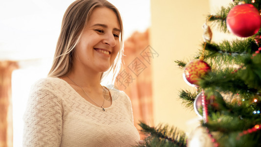 站在圣诞树上欢笑的女人肖像站在圣诞树上欢笑的年轻女孩肖像图片