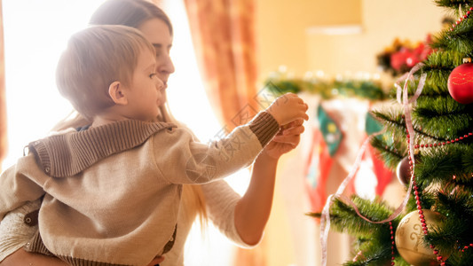 小男孩和妈一起装饰圣诞树的近照男孩和妈一起装饰圣诞树的近照图片