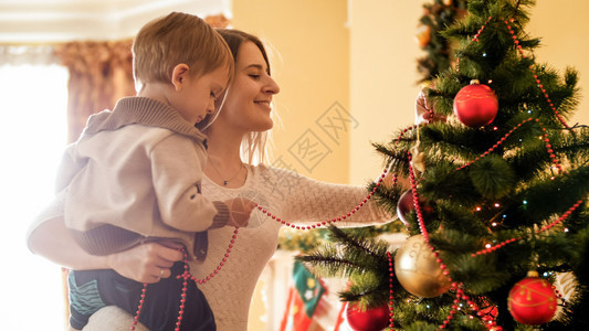 小男孩帮助母亲装饰圣诞树的肖像小男孩帮助母亲装饰圣诞树的雕像图片