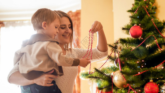 小男孩帮助母亲在客厅装饰圣诞树图片