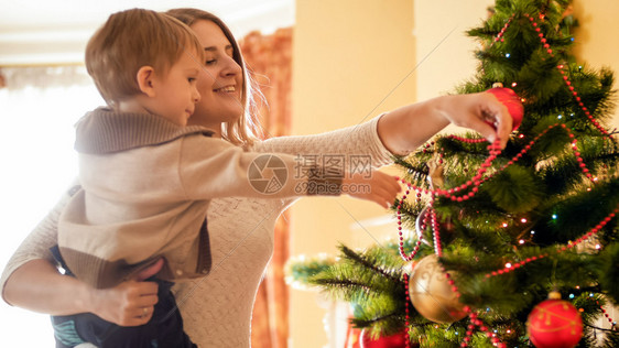 圣诞树上装饰红闪亮珠的男孩图片