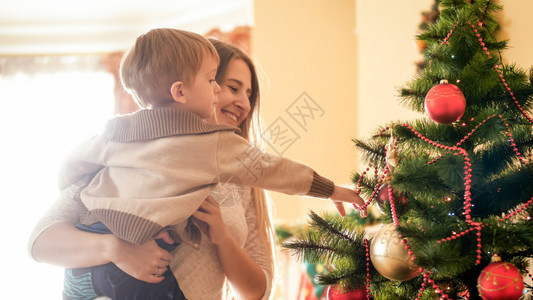 小男孩伸向圣诞树上的珠和小男孩的肖像伸向圣诞树上的珠和图片