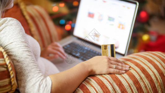 以信用卡和笔记本电脑制作圣诞节在线订单的年轻女近照图片