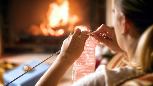 女青年在织羊毛围巾的同时在壁炉旁变暖图片