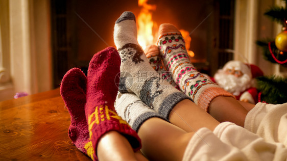 3人穿着编织的羊毛袜子在小屋壁炉上变暖3人穿着编织的羊毛袜子图片