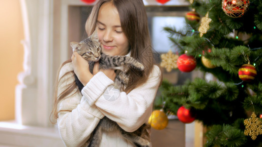 坐在圣诞树边的美丽棕发女人坐在圣诞树边围着小猫猫的美丽棕发女人肖像图片